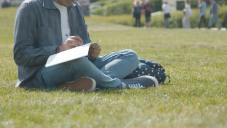 Handheld-Shot-of-Student-Writing-Notes-In-a-Park
